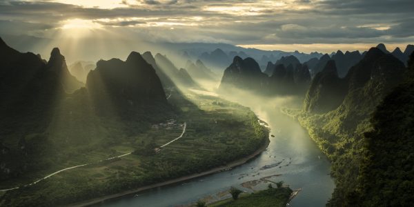 Sun beams on a misty morning on karst mountains and river