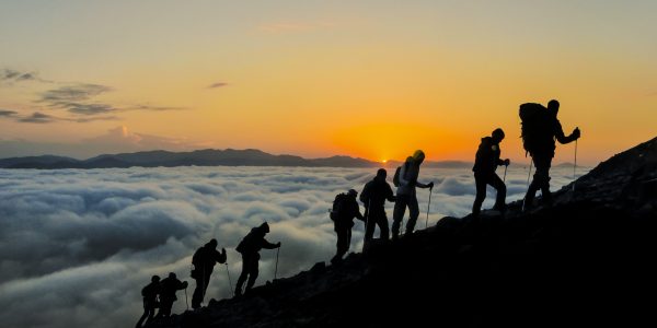 Silhouetten von Bergsteigern, die einen Gipfel erklimmen
