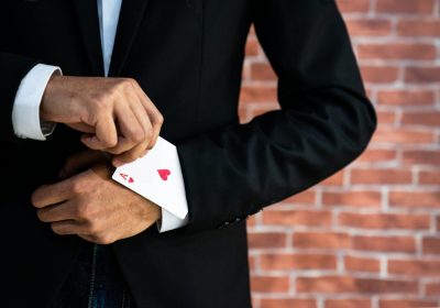 Abstraktes Bild eines Geschäftsmann der ein Pik Ass aus dem Ärmel zabuert als Metapher für "Open banking poker—Winner takes all"