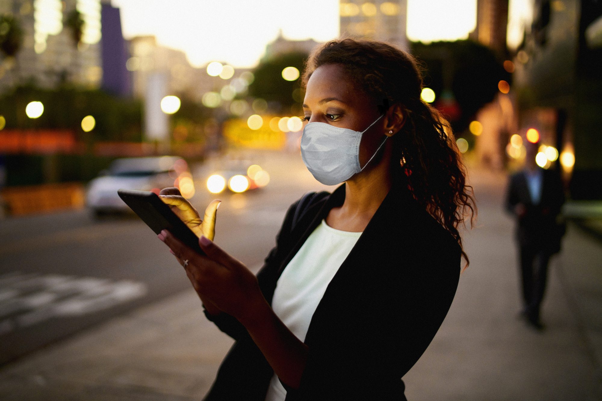Business-Frau mit Mund-Nasen-Maske blickt auf Smartphone-Display als Metapher für den "zeb.market flash Q2 2020 (Issue 33 – Juli 2020)"